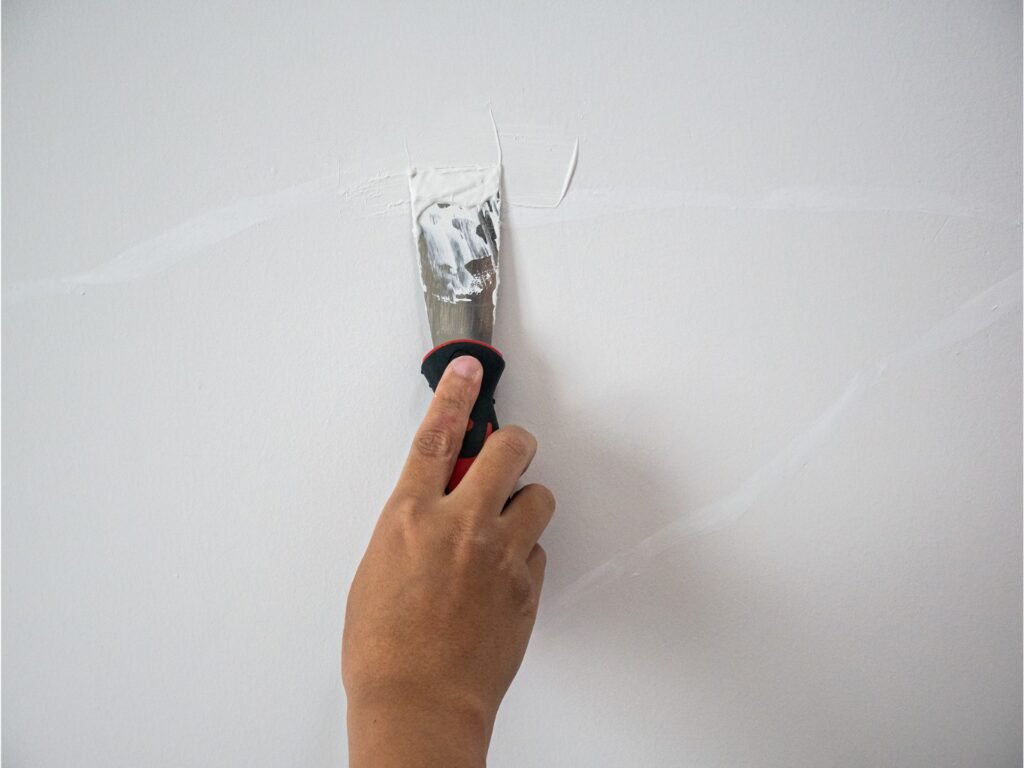 persona reparando grieta en pared con espatula